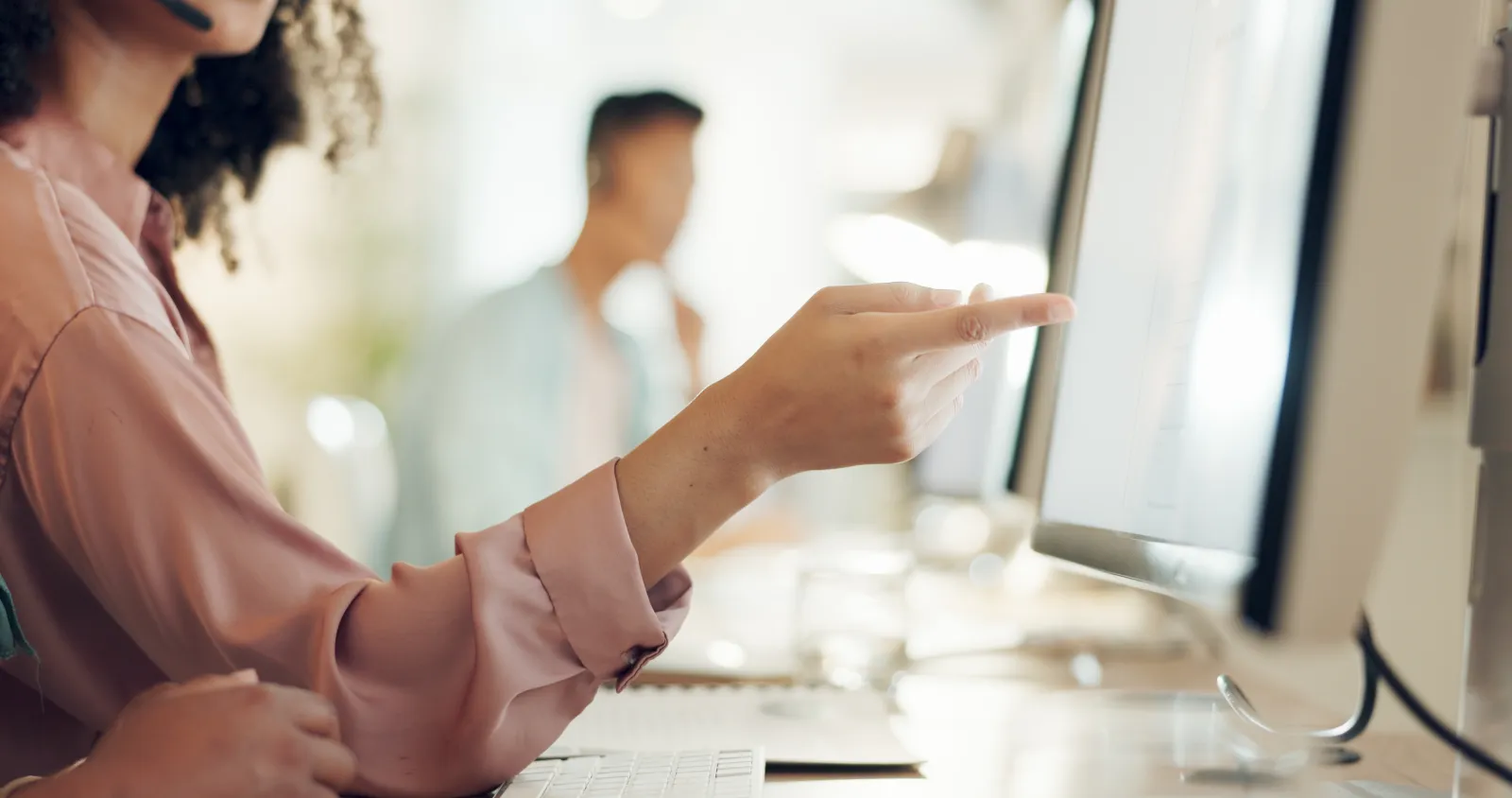 Person som pekar på innehåll på en datorskärm under ett möte