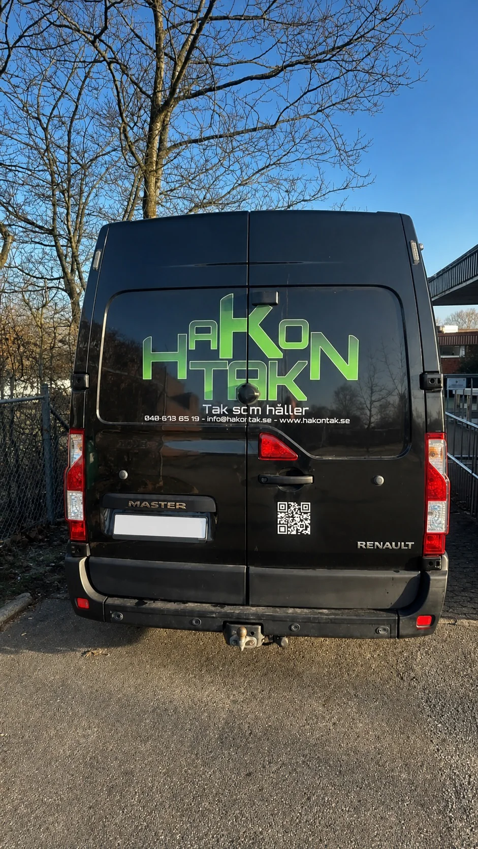 Hakon Taks gröna logotyp applicerad på en svart servicebil